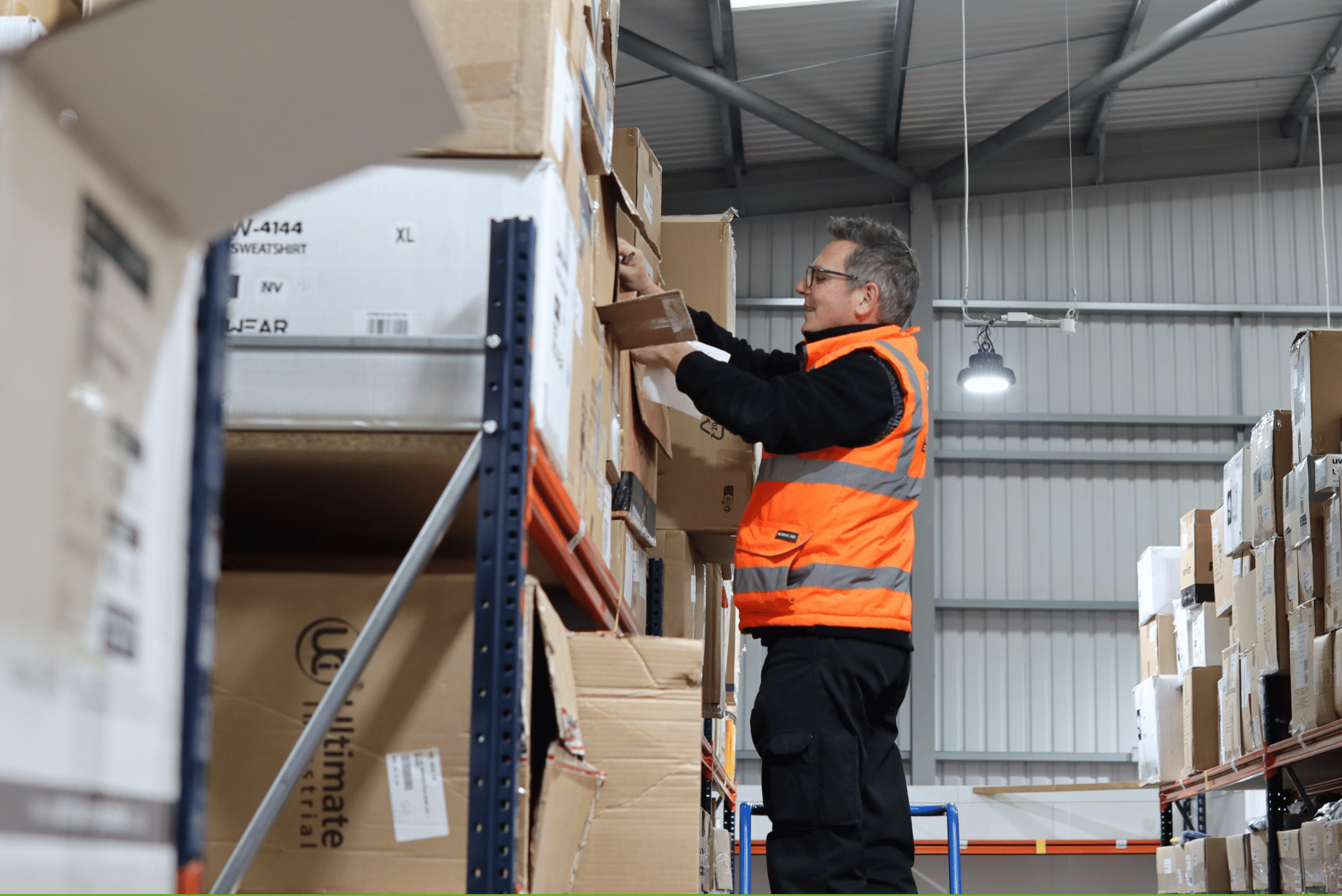 Man in hi-vis gilet inside a warehouse.